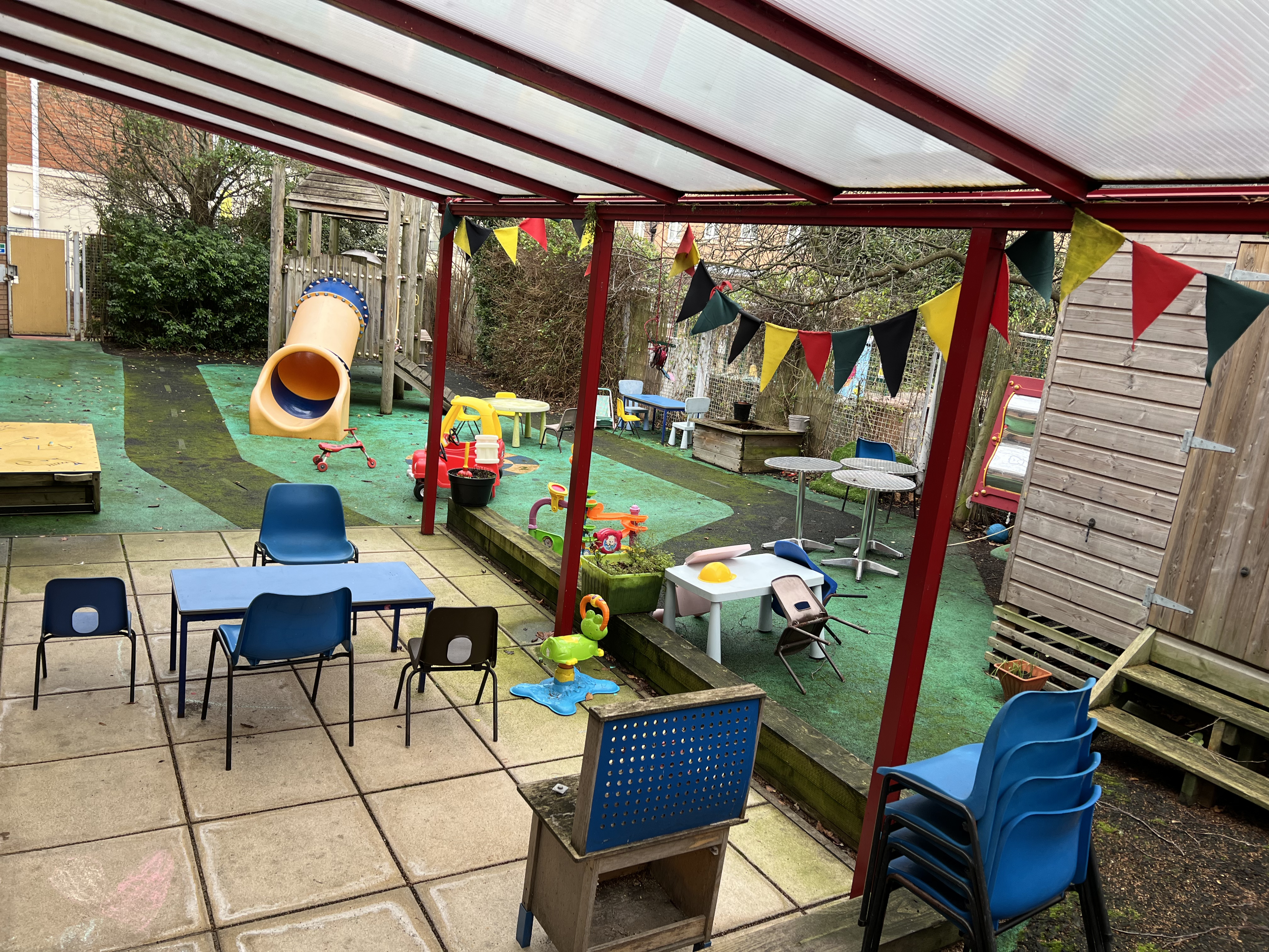 Children's outdoor enclosed play space with equipment and toys